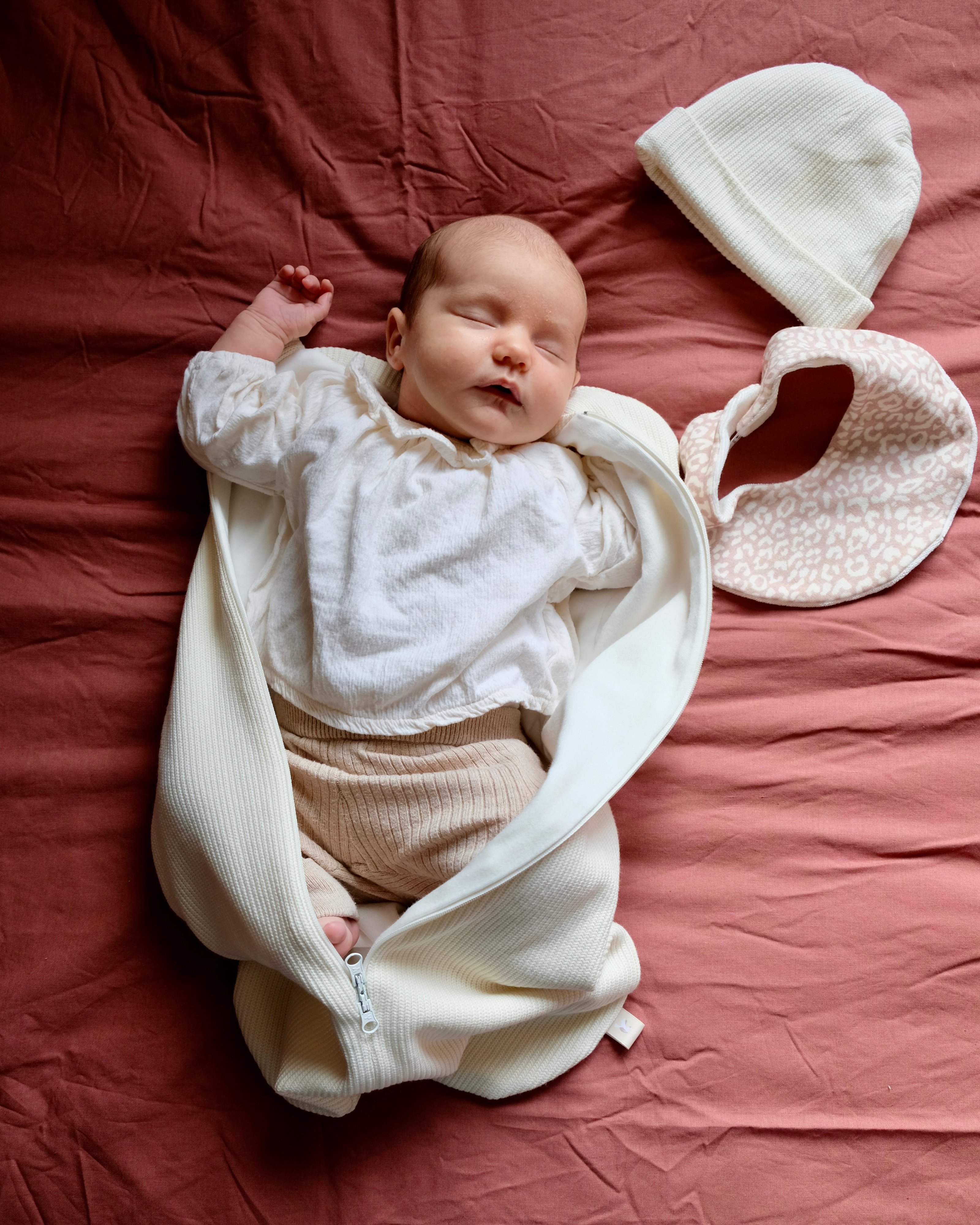 bébé avec bonnet, bavoir et emmailloteuse qui dort
