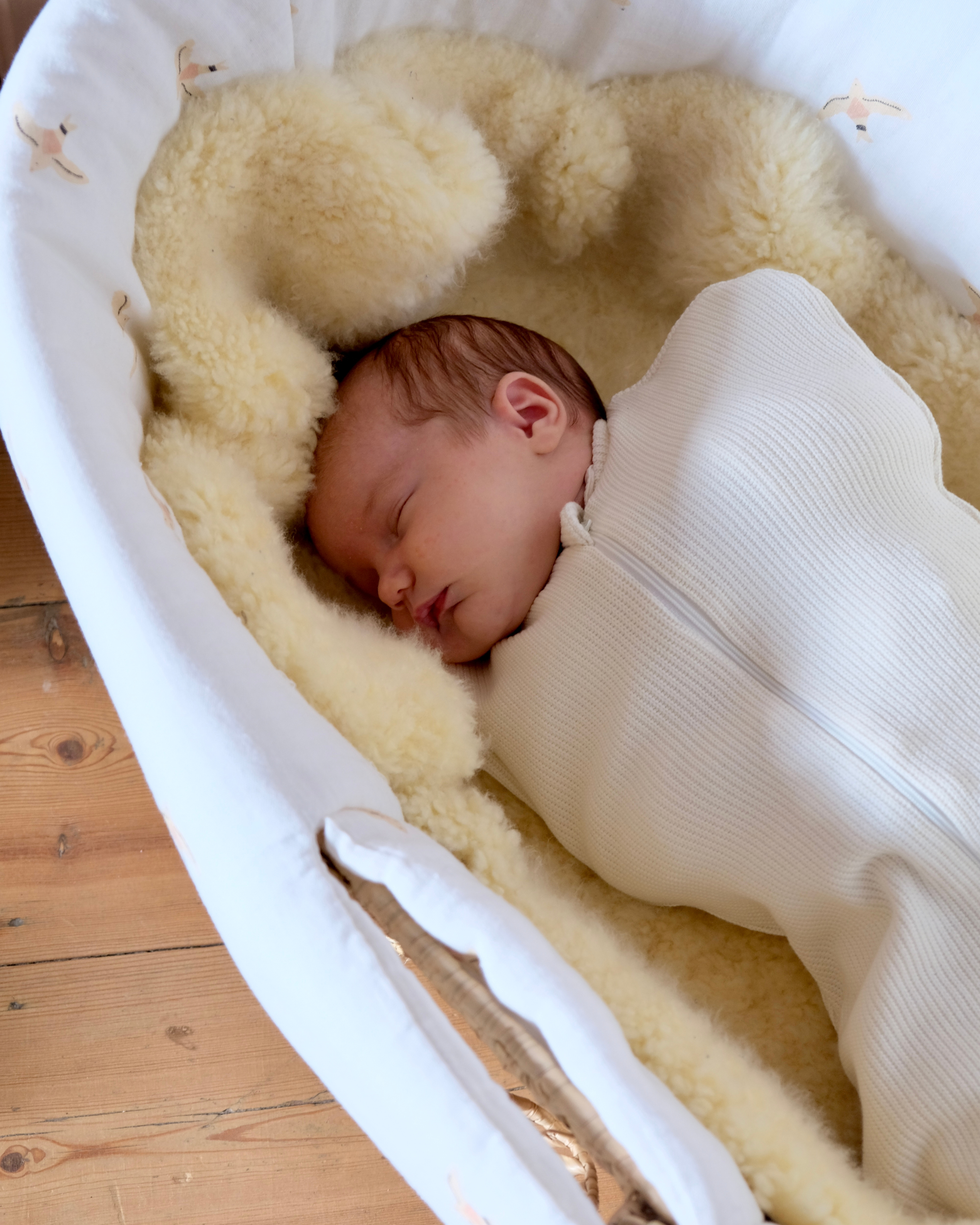 bébé dans son emmailloteuse blanche qui dort dans son couffin