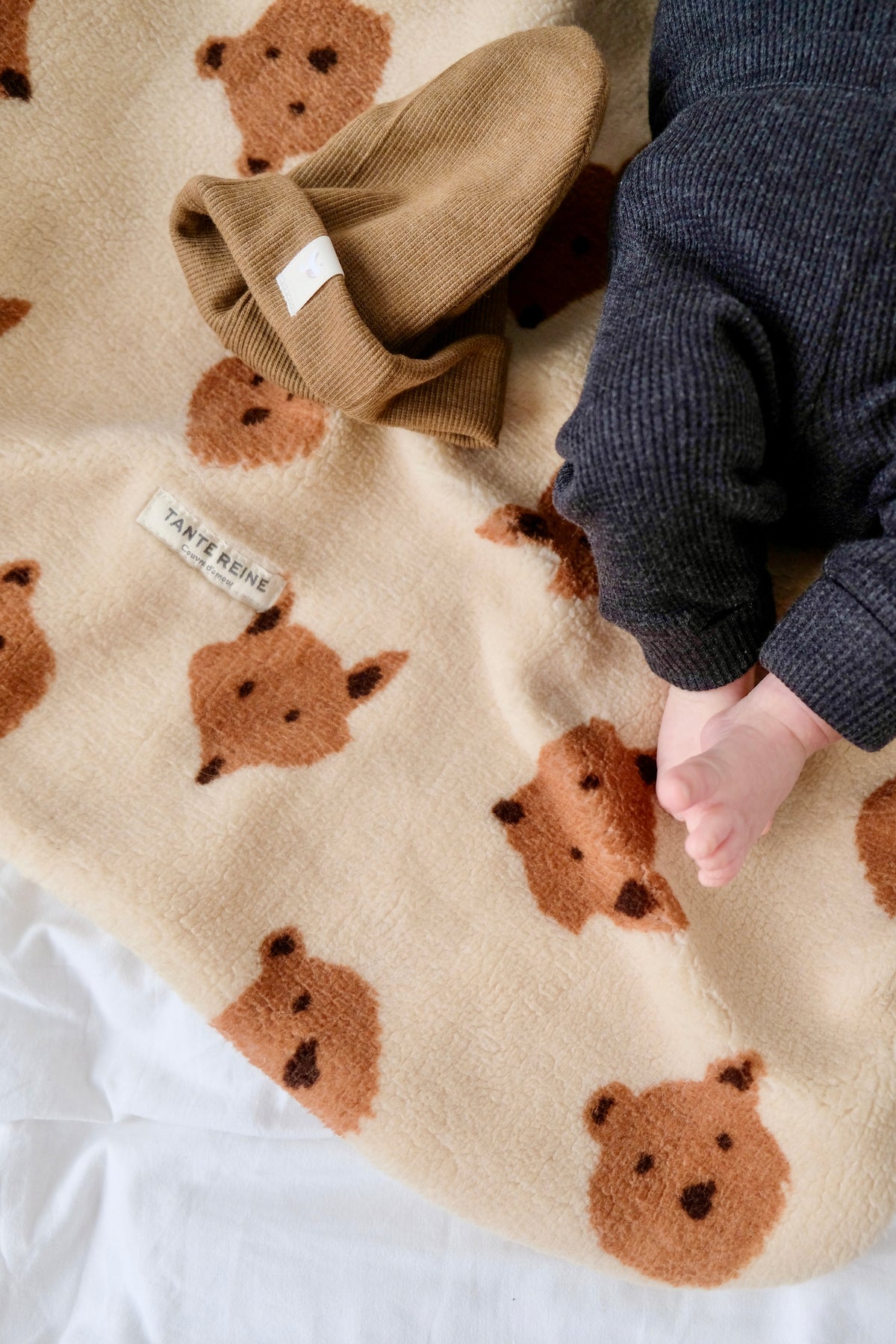 pieds de bébé sur couverture friends zoomée avec bonnet noisette