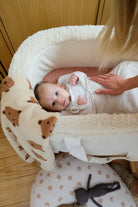 bébé emmailloté avec bras sortis se réveillant dans son couffin